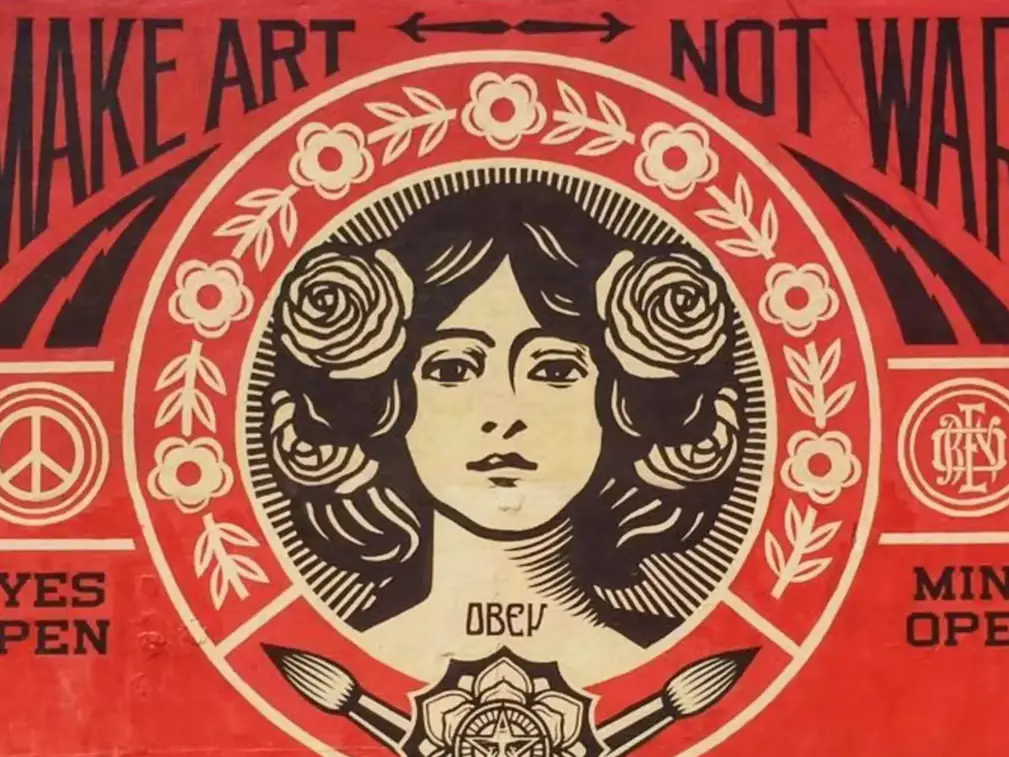 “Make Art Not War” mural detail – a portrait framed by roses and paintbrushes inside a red-and-cream ornamental circle.